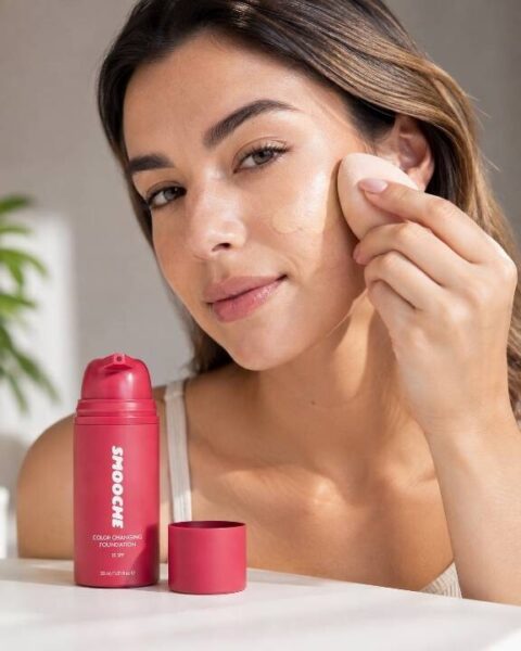 Woman applying Smooche Color Changing Foundation with a makeup sponge